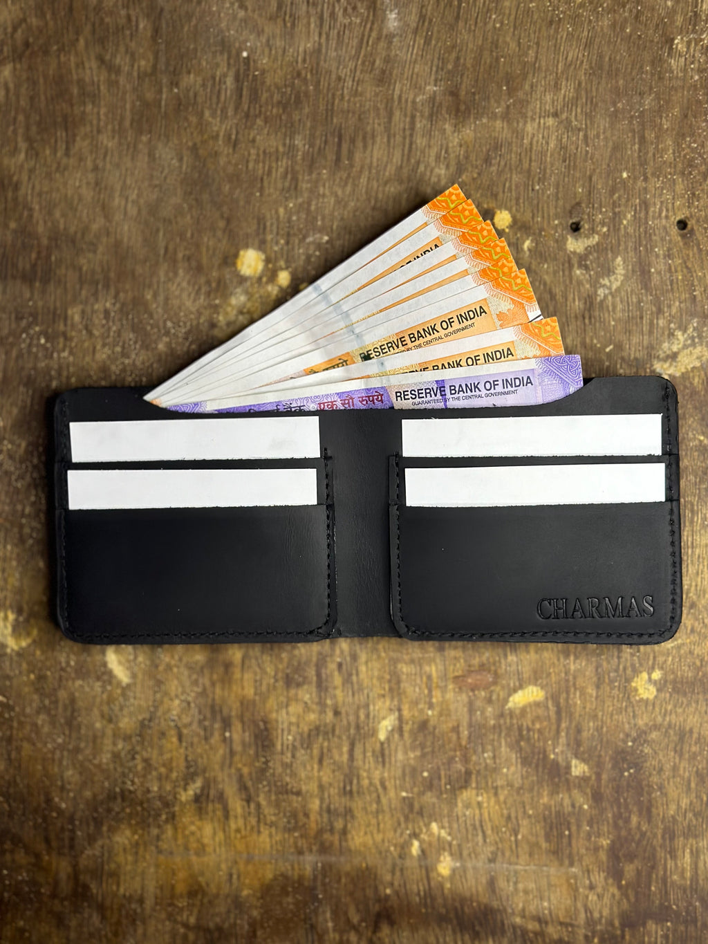 Black wallet with Indian currency notes on a textured brown background