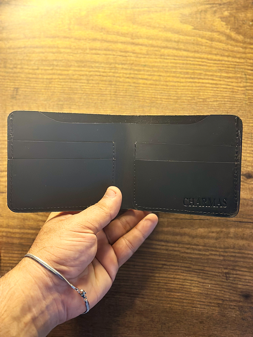Black wallet held by a hand on a wooden surface