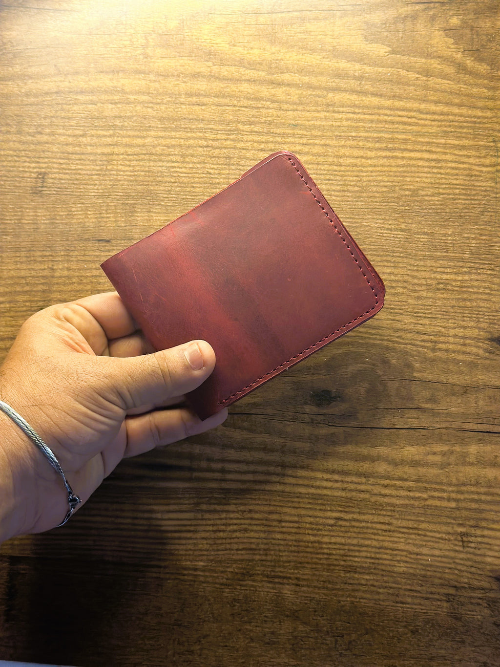 CHARMAS cherry maroon wallet held in hand lifestyle shot